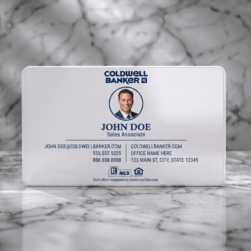 Solid white PVC business card featuring a clean, professional design with Coldwell Banker blue branding, circular photo, sans-serif typography, and real estate icons