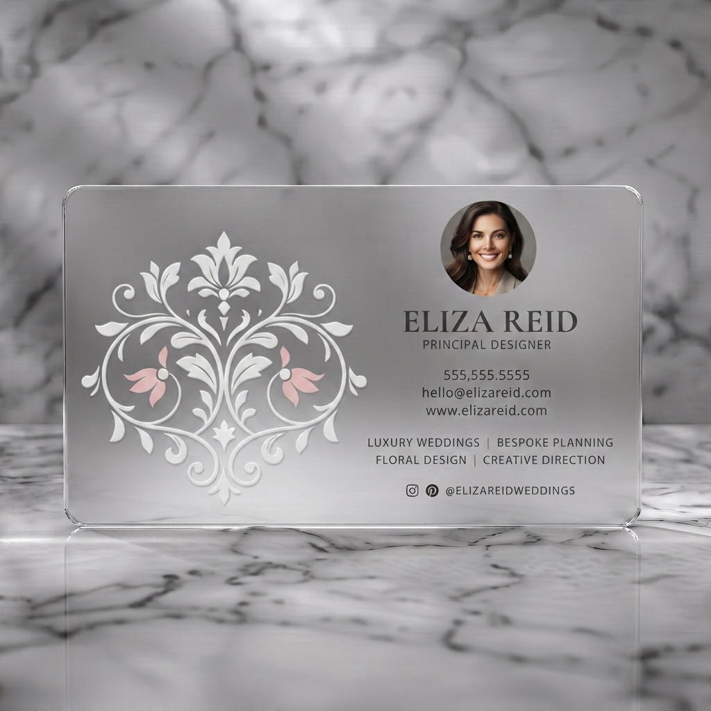 Frosted translucent plastic business card featuring elegant cream card with embossed floral pattern, charcoal text, gold/pink accents, and social icons