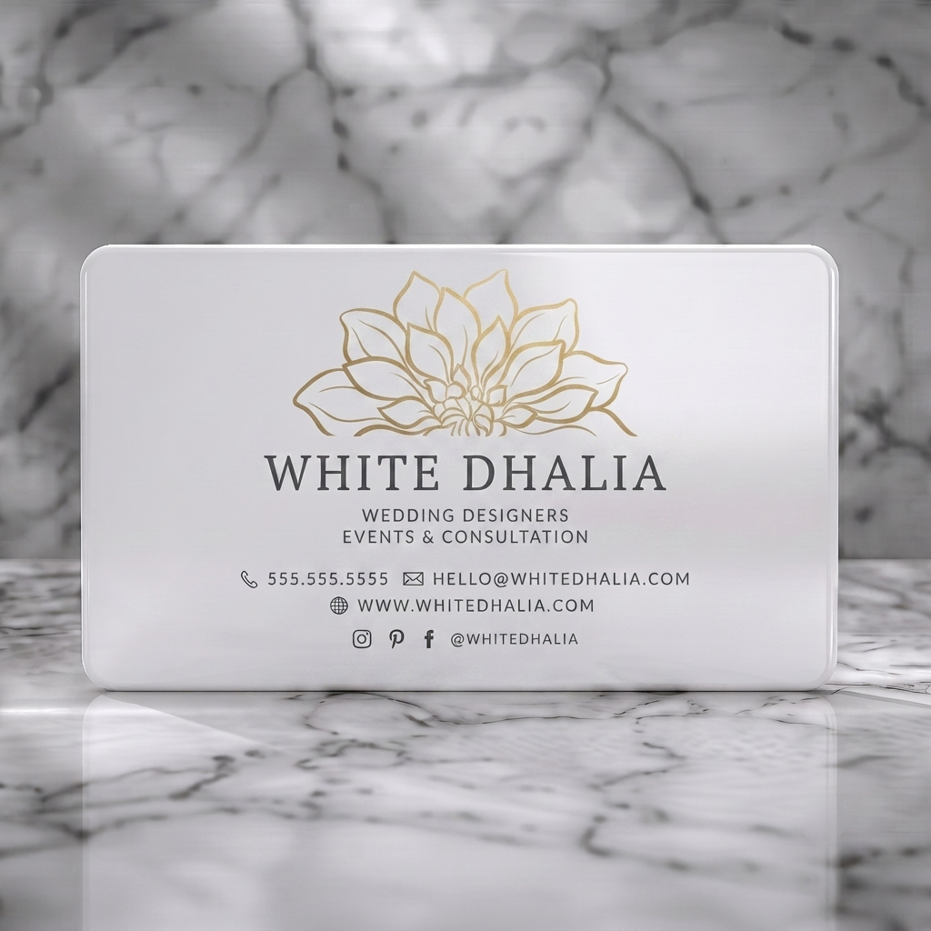 Solid white PVC business card featuring gold dahlia flower logo, elegant dark typography, and minimalist contact icons on a cream card