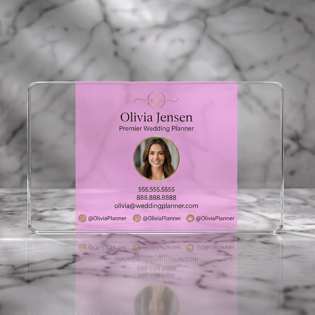 Clear plastic business card featuring an elegant, personalized design with a soft pink background, gold accents, modern typography, and social icons